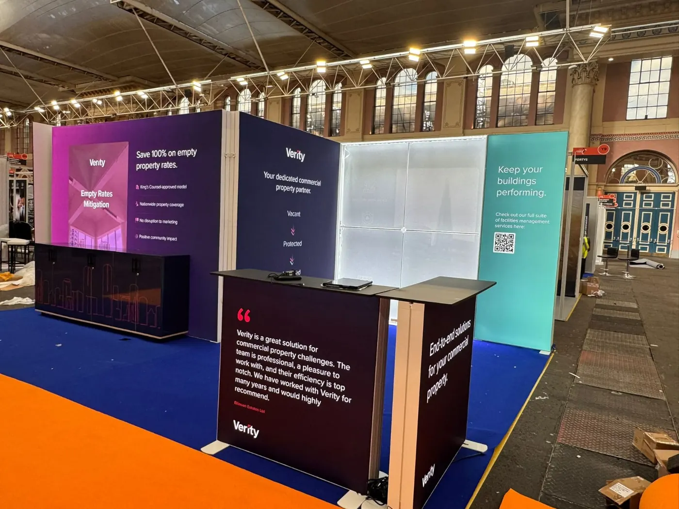 An open-plan stand with light-box walls and a counter