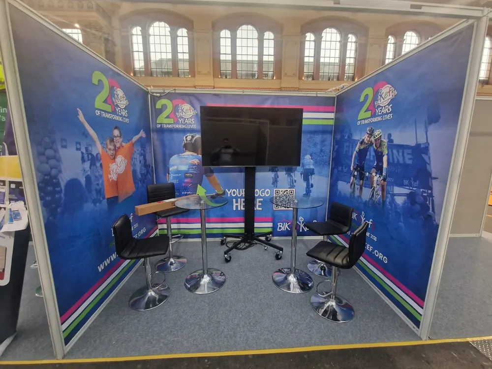 A shell-scheme stand with a screen and bar stools